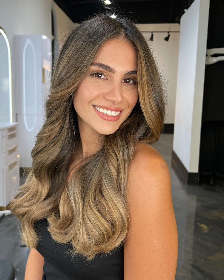 Woman with long, wavy hair smiling in a salon setting